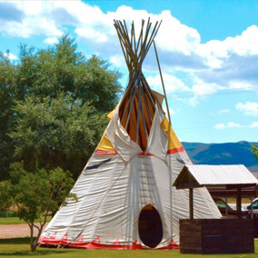 Large teepee next to a well and tree