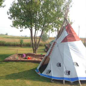 Small tepee beside a sand pit in the shade of a tree